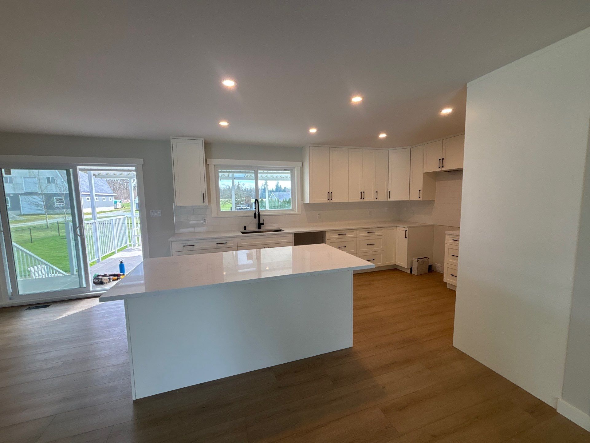 White shaker kitchen with natural light from sliding door, full upper and lower cabinets — Langley, BC