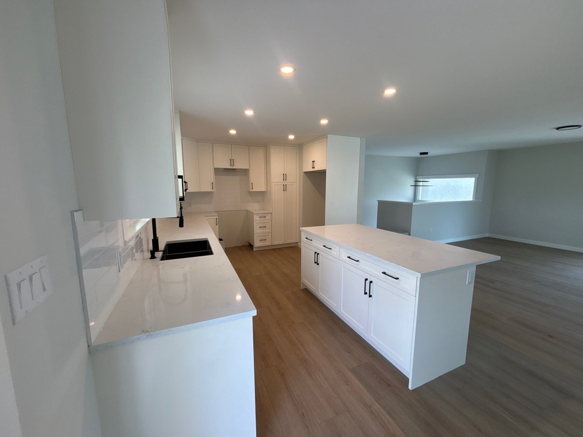 White shaker kitchen with large island, quartz countertop and matte black hardware — Langley, BC